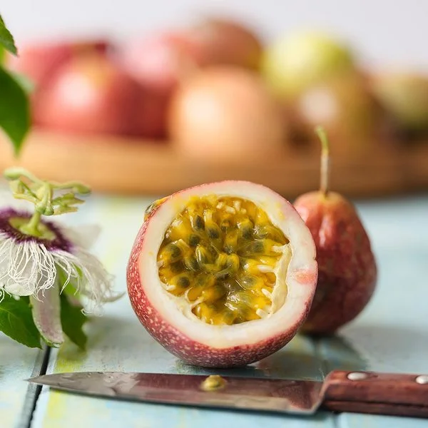 Eine Passionsfrucht liegt durchgeschnitten auf einem Tisch. Das Fruchtfleisch und die Kerne sind gut zu erkennen.