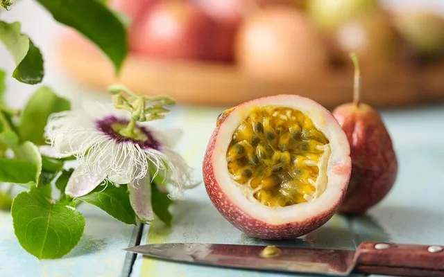 Eine Passionsfrucht liegt durchgeschnitten auf einem Tisch. Das Fruchtfleisch und die Kerne sind gut zu erkennen.