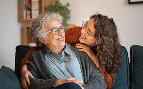 Eine junge und ältere Frau halten sich im Arm und lachen gemeinsam.
