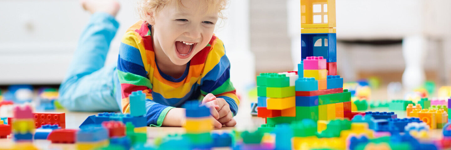 Ein kleiner Junge spielt mit Bauklötzen, denn Spielen ist gesund für Baby und Kleinkind.