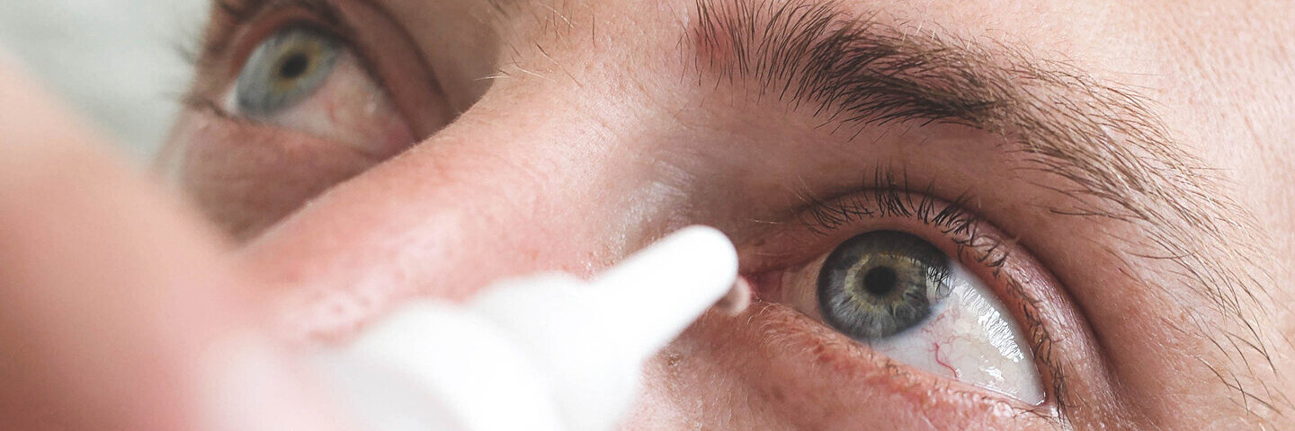 Ein Mann tropft sich Augentropfen in die Augen.