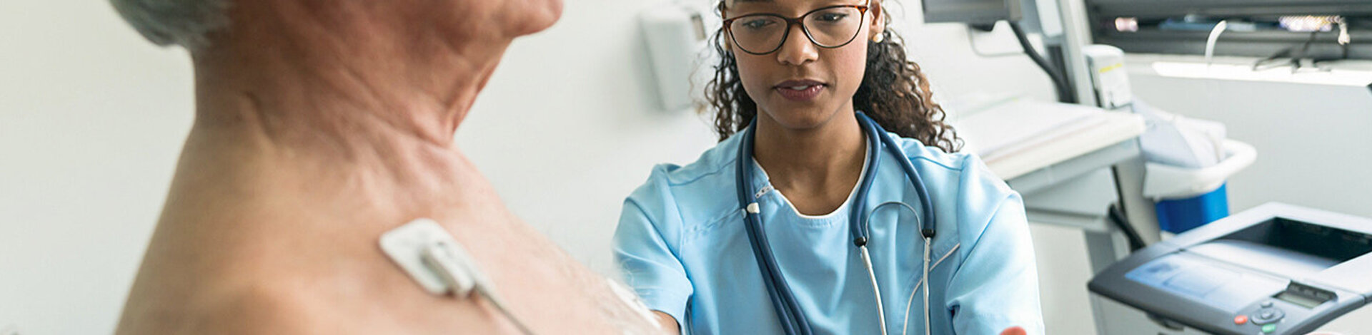 Eine Ärztin beobachtet einen älteren Patienten bei einem Belastungstest.