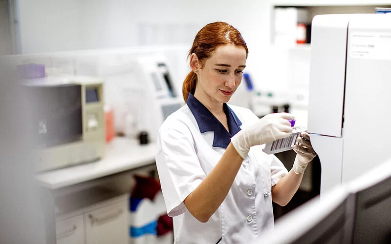 Eine medizinisch-technische Laborassistentin hält einen Halter für Serumröhrchen in den Händen, um eine Probe auf Agranulozytose zu untersuchen.