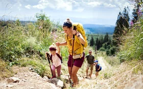 Eine Mutter und ein Vater sind beim Erlebniswandern mit ihren Kindern zu sehen.