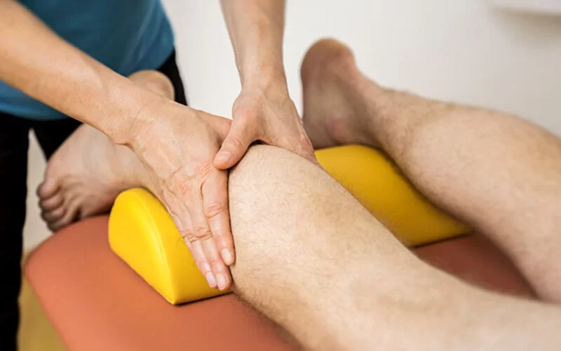 Eine Person erhält eine physiotherapeutische Behandlung an den Waden.