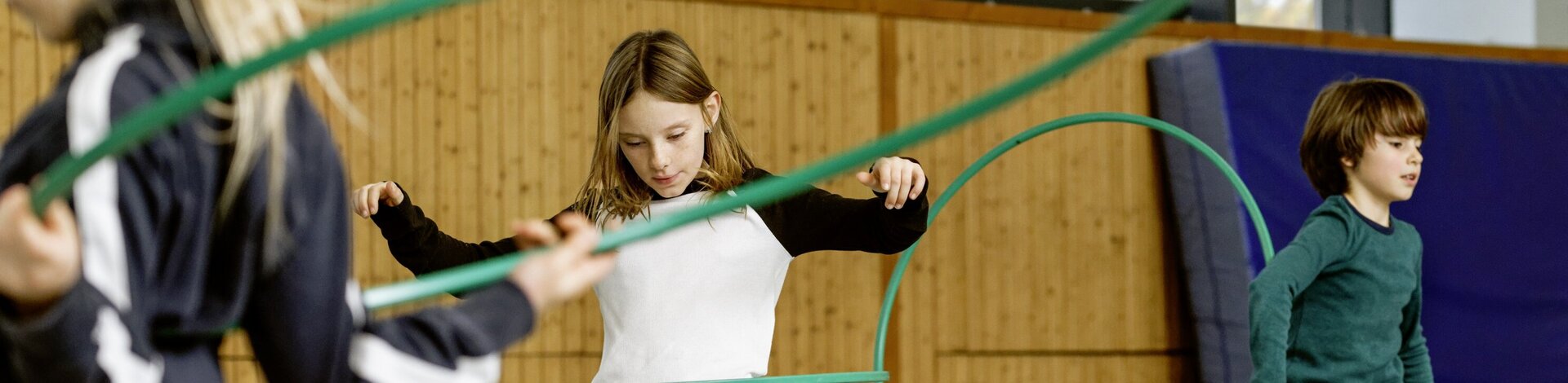 Kinder im Sportunterricht mit Reifen.