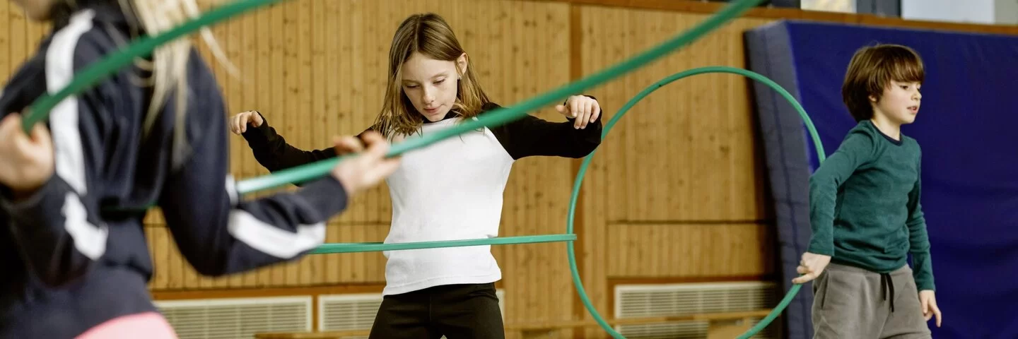 Kinder im Sportunterricht mit Reifen.