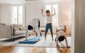 Ein Vater macht zu Hause Sport mit seinen beiden Kindern.