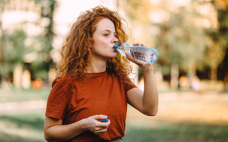 Eine junge Frau trinkt Wasser.