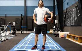 Olympiateilnehmer Christian Erhoff mit einem Ball in der Hand steht in einer Sporthalle.