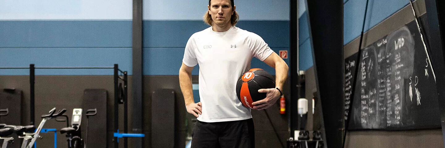 Olympiateilnehmer Christian Erhoff mit einem Ball in der Hand steht in einer Sporthalle.