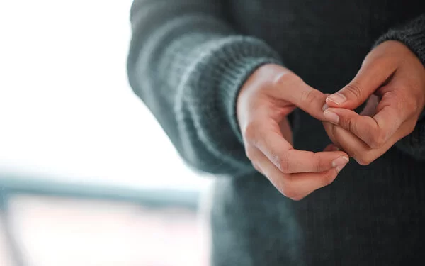 Frau zeigt ihre Hände. Sie leidet unter Paronychie, die auch als Nagelfalzentzündung oder Nagelwallentzündung bezeichnet wird