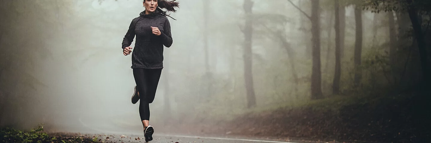 Frau erlebt ein Runner’s High beim Joggen auf einer Landstraße.