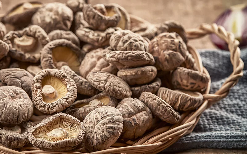 Ein flacher Weidenkorb mit getrockneten Shiitake-Pilzen.