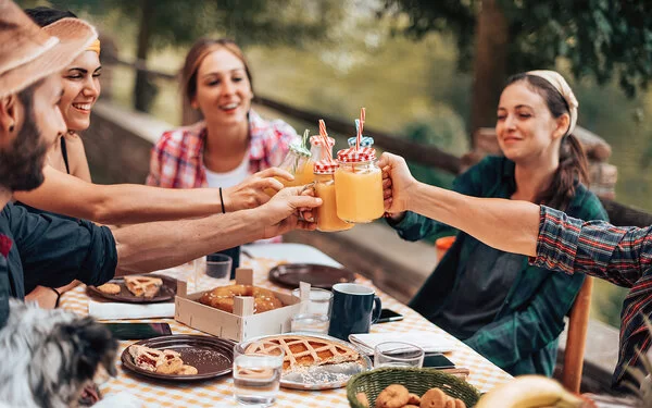 Eine Gruppe Freunde prostet sich mit gesunden Smoothies zu.