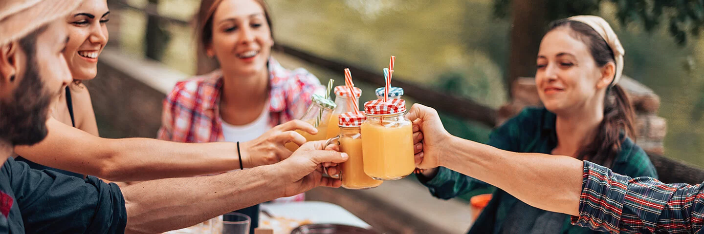 Eine Gruppe Freunde prostet sich mit gesunden Smoothies zu.