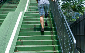 Ein Mann mit Beinprothese geht eine Treppe hoch.