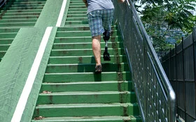 Ein Mann mit Beinprothese geht eine Treppe hoch.