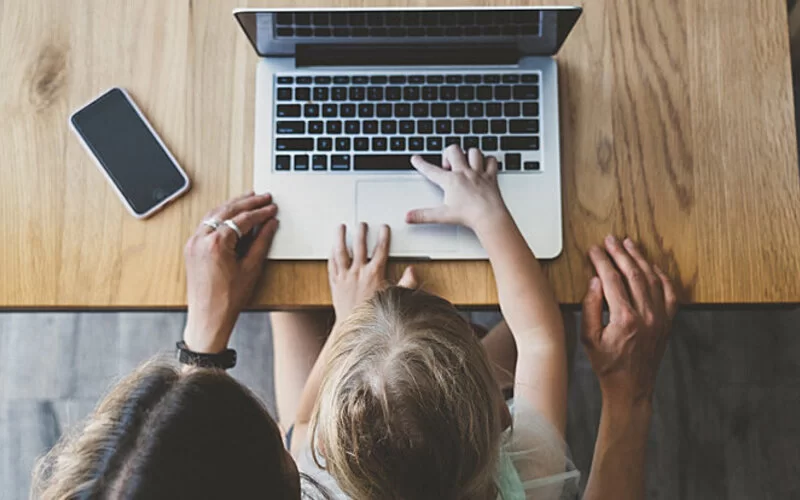 Mutter und Tochter sitzen gemeinsam am Laptop.