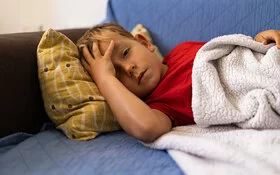 Ein Junge, der an einer Meningitis erkrankt ist, liegt auf dem Sofa.