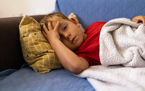 Ein Junge, der an einer Meningitis erkrankt ist, liegt auf dem Sofa.