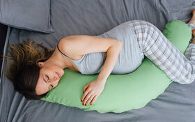 Schwangere Frau schläft gut, weil sie ein Seitenschläferkissen nutzt.