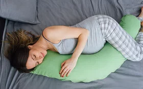 Schwangere Frau schläft gut, weil sie ein Seitenschläferkissen nutzt.