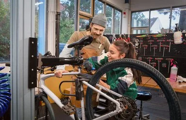 Ausbilder erklärt einer Auszubildenden die Reparatur eines Fahrrads in der Werkstatt.