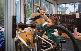 Ausbilder erklärt einer Auszubildenden die Reparatur eines Fahrrads in der Werkstatt.