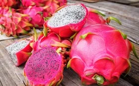 Mehrere Drachenfrüchte liegen teilweise aufgeschnitten auf einem Tisch.