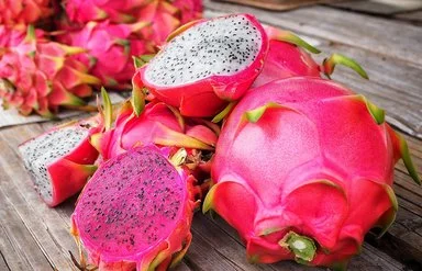 Mehrere Drachenfrüchte liegen teilweise aufgeschnitten auf einem Tisch.