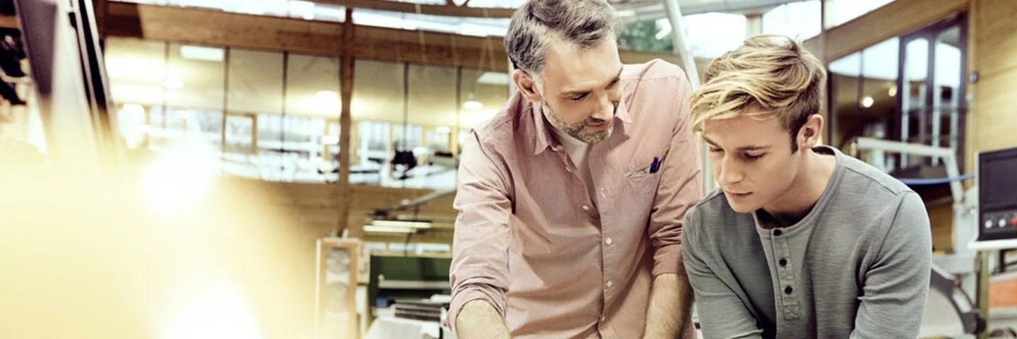 Ein Mitarbeiter erklärt einem Auszubildenden etwas anhand einer Skizze. Was die AOK für Azubis bietet, erfahren Sie hier.  