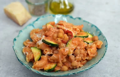 Vegetarische One-Pot-Pasta mit Kichererbsen nach einem Rezept von Felicitas Then, angerichtet auf einem türkisfarbenen Teller auf einer hellen Arbeitsplatte.