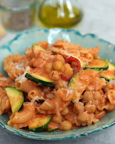Vegetarische One-Pot-Pasta mit Kichererbsen nach einem Rezept von Felicitas Then, angerichtet auf einem türkisfarbenen Teller auf einer hellen Arbeitsplatte.
