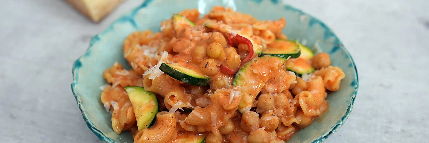 Vegetarische One-Pot-Pasta mit Kichererbsen nach einem Rezept von Felicitas Then, angerichtet auf einem türkisfarbenen Teller auf einer hellen Arbeitsplatte.