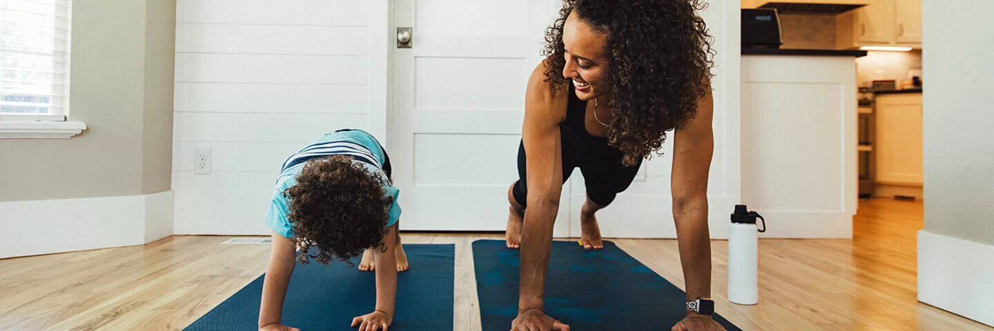 Eine Mutter macht mit ihrem Kind Sport auf Fitnessmatten.