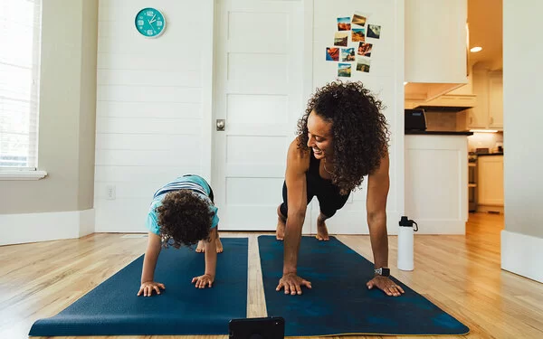 Eine Mutter macht mit ihrem Kind Sport auf Fitnessmatten.