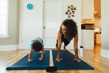 Eine Mutter macht mit ihrem Kind Sport auf Fitnessmatten.