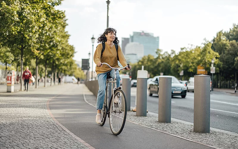 Eine Frau fährt Fahrrad auf einem Radweg in der Stadt.