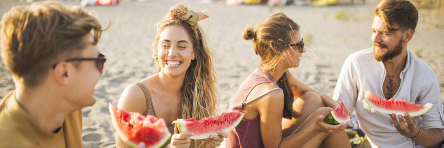 Lachende Menschen am Strand mit Wassermelone
