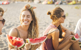 Lachende Menschen am Strand mit Wassermelone