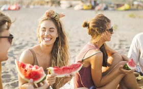 Lachende Menschen am Strand mit Wassermelone