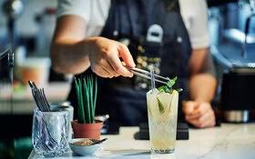 Barkeeper garniert einen alkoholfreien Gin-Cocktail mit Minze.