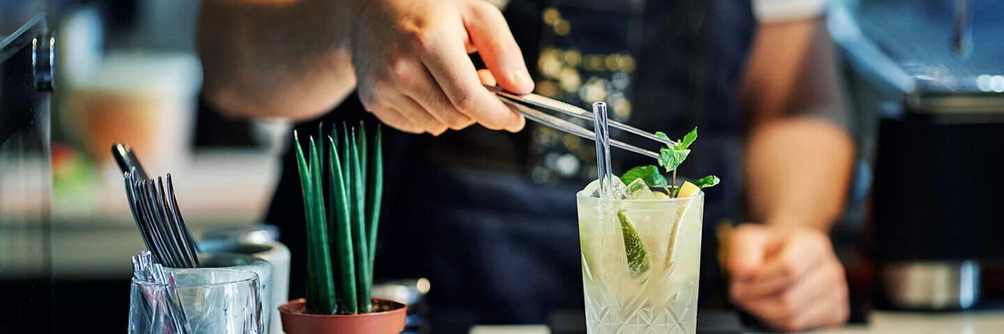 Barkeeper garniert einen alkoholfreien Gin-Cocktail mit Minze.