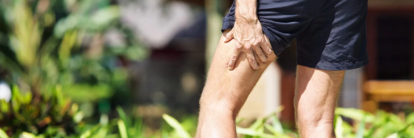 Ein Jogger greift mit der Hand an seinen schmerzenden Oberschenkel.