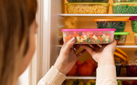 Frau möchte Lebensmittel frisch halten und verstaut sie im Kühlschrank.