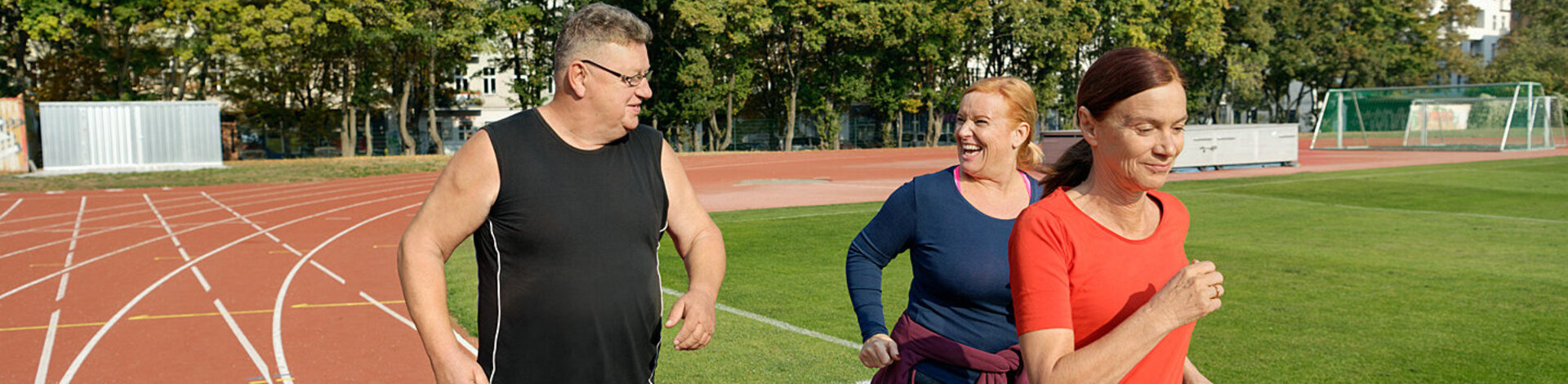 Zwei Frauen und ein Mann nehmen an einem Lauftraining teil. Beim Abnehmen helfen ihnen Kursangebote der AOK.
