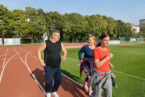 Zwei Frauen und ein Mann nehmen an einem Lauftraining teil. Beim Abnehmen helfen ihnen Kursangebote der AOK.