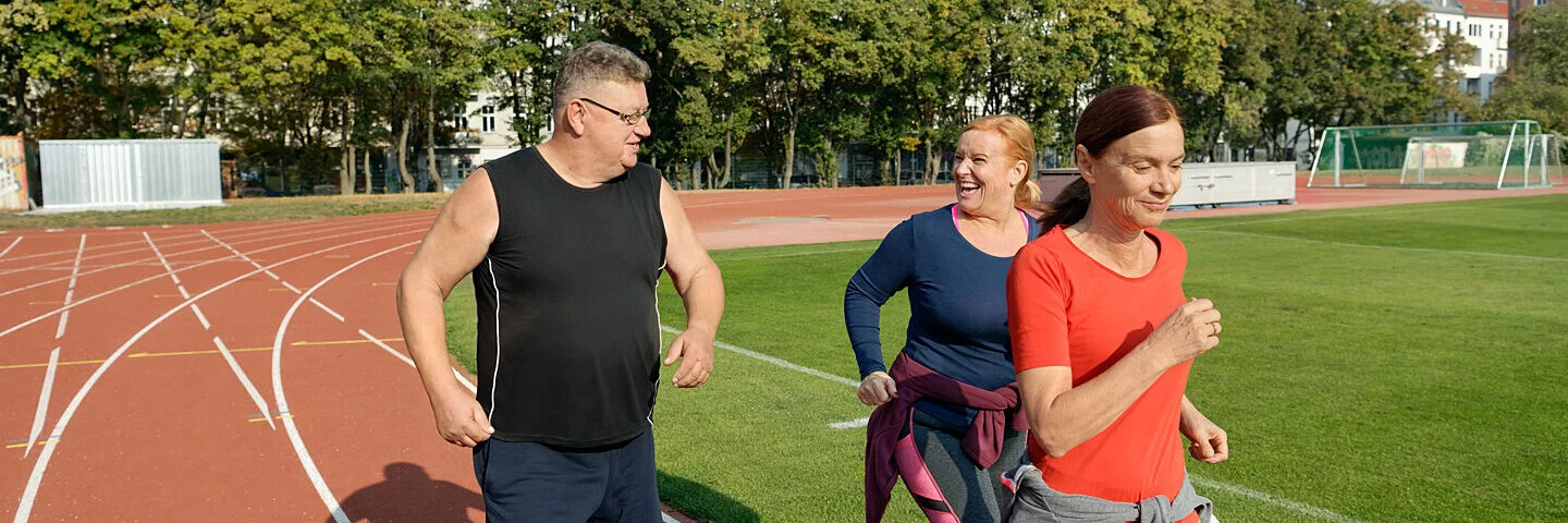 Zwei Frauen und ein Mann nehmen an einem Lauftraining teil. Beim Abnehmen helfen ihnen Kursangebote der AOK.