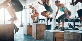Eine Fitness-Gruppe springt auf unterschiedlich hohe Holzblöcke.
